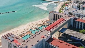 Un hôtel situé sur la côte, doté d’une piscine, d’un accès à la plage et d’une jetée qui s’avance dans la mer.