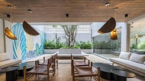 Un intérieur moderne avec un plafond en bois, une grande fresque murale et un espace détente comprenant un canapé et des fauteuils.