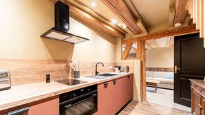 A modern kitchen with wooden beams, a built-in oven, and a sink. - Appartement Château Pape - A quelques minutes de Colmar (Eguisheim)
