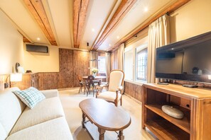 Ein gemütliches Wohnzimmer mit Holzboden, einem Flachbildfernseher, einer Couch, einem Couchtisch und einem Essbereich mit Tisch und Stühlen.