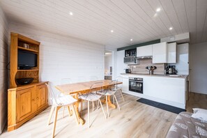 Eine kompakte Küche mit weißen Schränken, einem Holztisch und einem eingebauten Backofen.