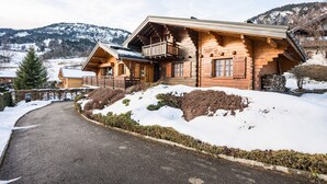 Eine Holzhütte mit Balkon, umgeben von verschneiter Landschaft und Bergen.
