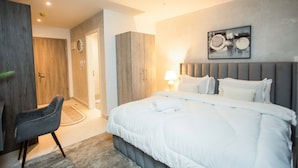 A modern bedroom with a large bed, a chair, and a wardrobe. - Serene New Studio Apartment @ The Bantree (Accra)