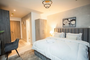 Ein modernes Schlafzimmer mit einem großen Bett, einem Sessel und einem Kleiderschrank.