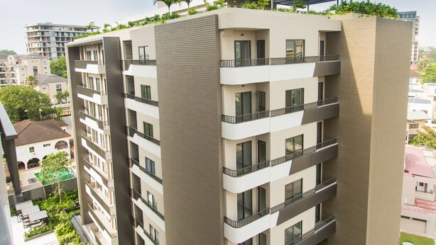A high-rise building with multiple balconies, a rooftop garden, and a green lawn area. - Serene New Studio Apartment @ The Bantree (Accra)
