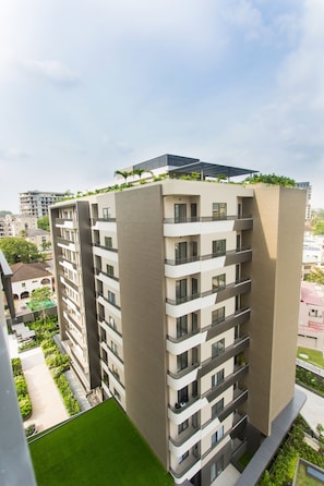 A high-rise building with multiple balconies, a rooftop garden, and a green lawn area. - Serene New Studio Apartment @ The Bantree (Accra)