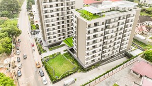 A multi-story residential building with balconies, a green rooftop garden, and a central courtyard. - Serene New Studio Apartment @ The Bantree (Accra)