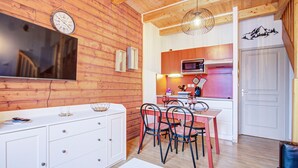 Eine moderne Küche mit Holzwänden, einem Essbereich mit Metallstühlen und einem weißen Schrank mit Schubladen.