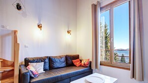 Ein modernes Wohnzimmer mit einer Ledersofa, einem weißen Tisch und einem großen Fenster mit weitreichendem Ausblick.