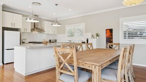 Cocina moderna con armarios blancos, una isla central e iluminación colgante.