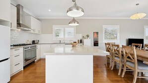 Una cocina moderna con armarios blancos, una isla central y sillas de madera.
