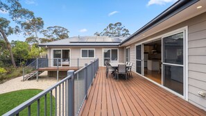 A modern house with a deck, a dining area, and a kitchen visible through glass doors. - Mirrabel in Blackheath (Blackheath)