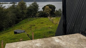 Blick auf eine Wiese mit einem Gewässer und Bergen im Hintergrund.