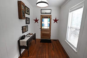 A hallway with a wooden floor, a door with glass panels, and star decorations on the wall. - The Sago Palm House (Thomasville)