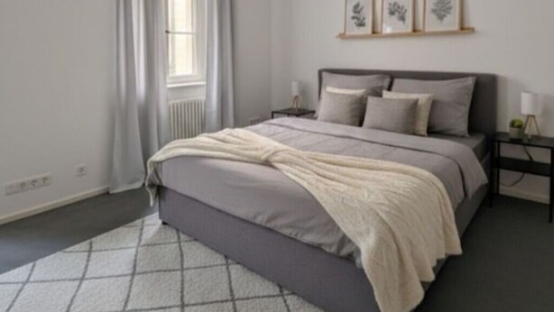 Ein Schlafzimmer mit einem Bett, Nachttischen, einem Fenster mit Vorhängen und gerahmten Kunstwerken an der Wand.