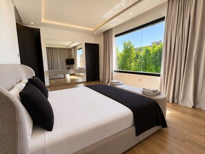 A modern bedroom with a large bed, a TV, and a view of greenery outside. - Palais Zahira (Marrakech)
