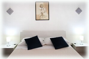 Une chambre à coucher comprenant un lit, deux tables de chevet et une œuvre d’art accrochée au mur.