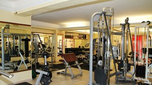 Une salle de sport équipée de divers appareils d’exercice, de miroirs et d’un banc.