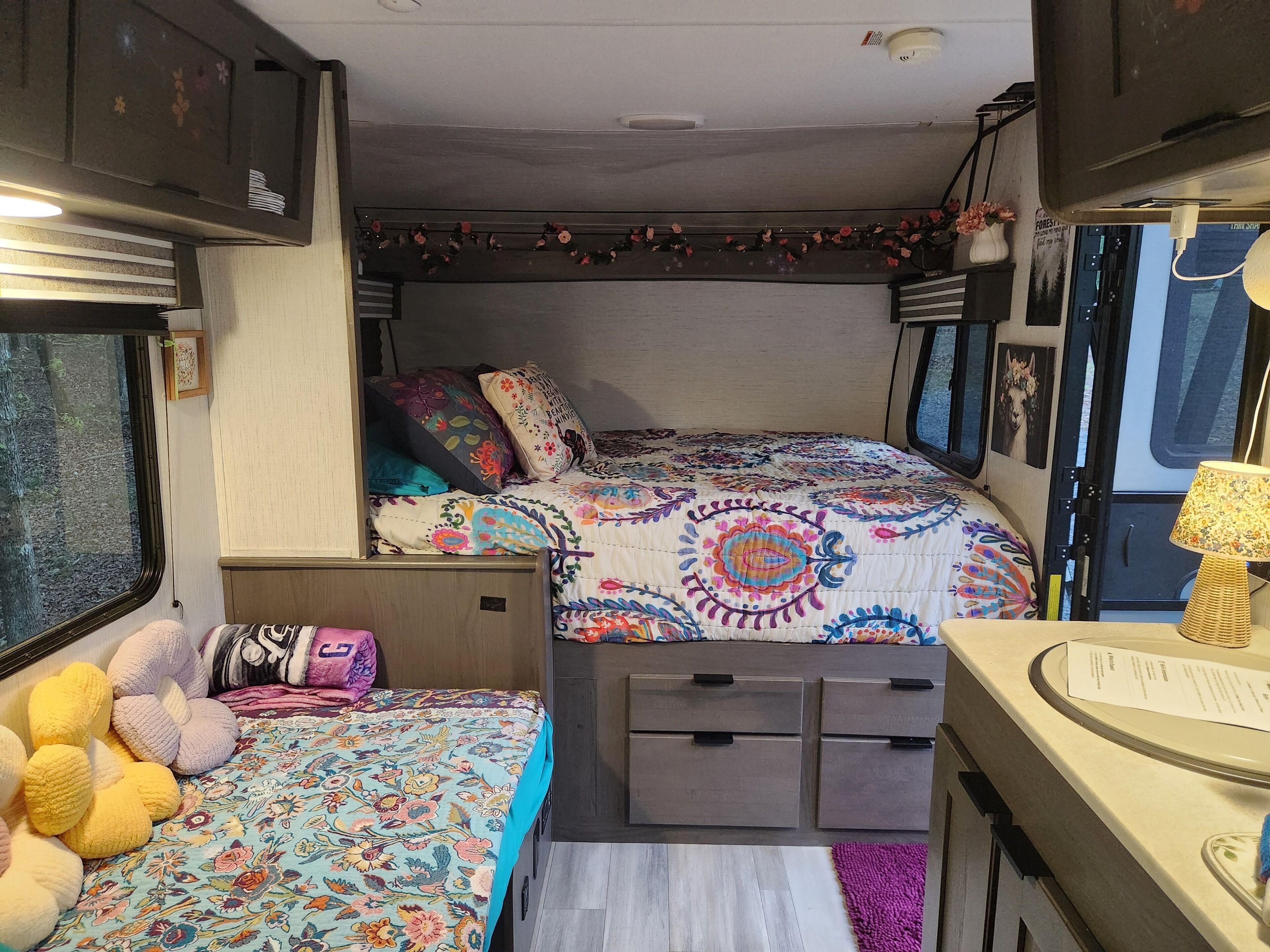 Interior acogedor de una caravana con dos camas, un escritorio pequeño y una ventana.
