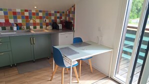 A modern kitchen with a colorful backsplash, a dining table with chairs, and a sliding glass door leading to a balcony. - o\tSelf-contained studio in house 3 km from Annecy town center, (Seynod)