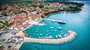 An aerial view of a coastal town with a marina, boats, and a prominent church. - Villa Nina Apartments Two-room apartment 2+2 for 4 persons (Fazana)