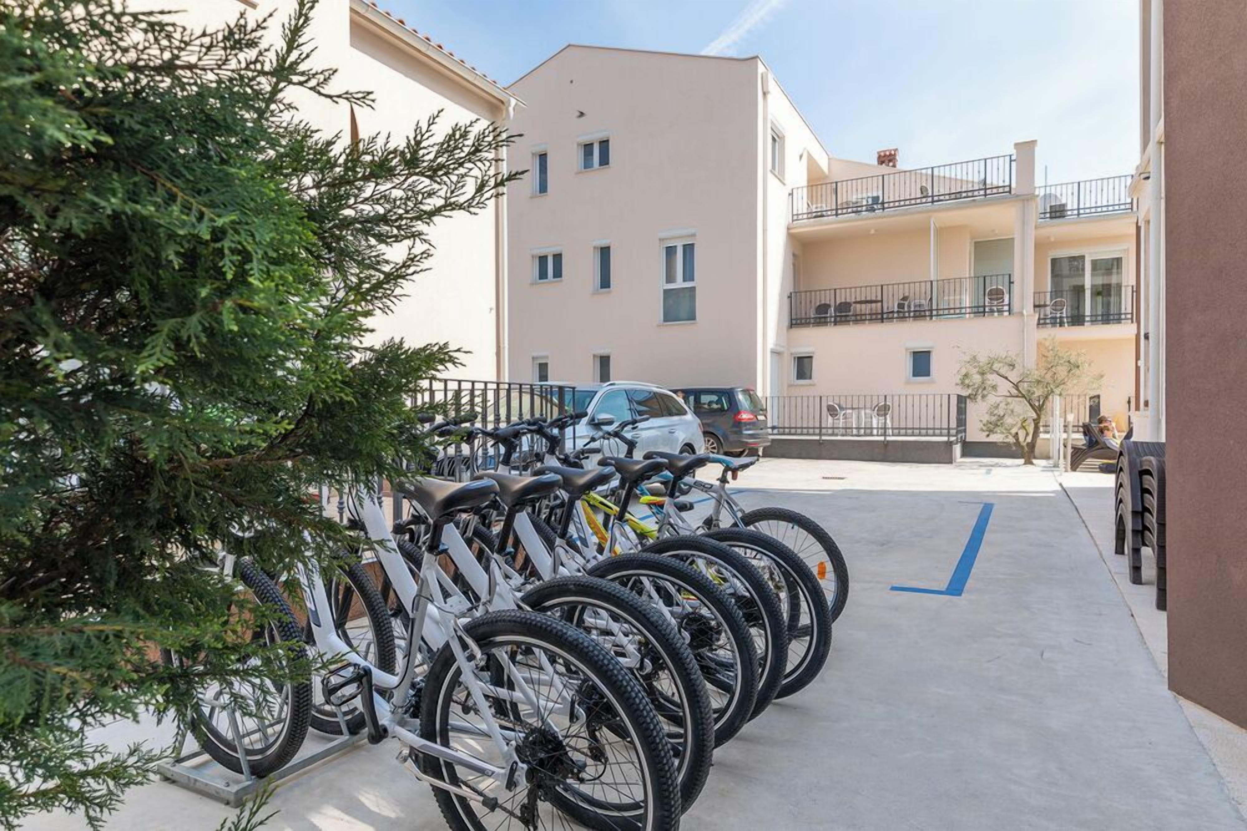 Varias bicicletas estacionadas en un área designada para bicicletas, con un edificio al fondo.