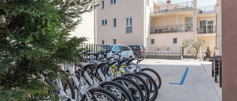 Varias bicicletas estacionadas en un área designada para bicicletas, con un edificio al fondo.