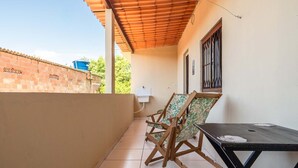 A balcony with a tiled floor, two wooden chairs, a table, and a water tank on the adjacent building. - Casa a 900m da Praia do Pontal em Cabo Frio (Cabo Frio)