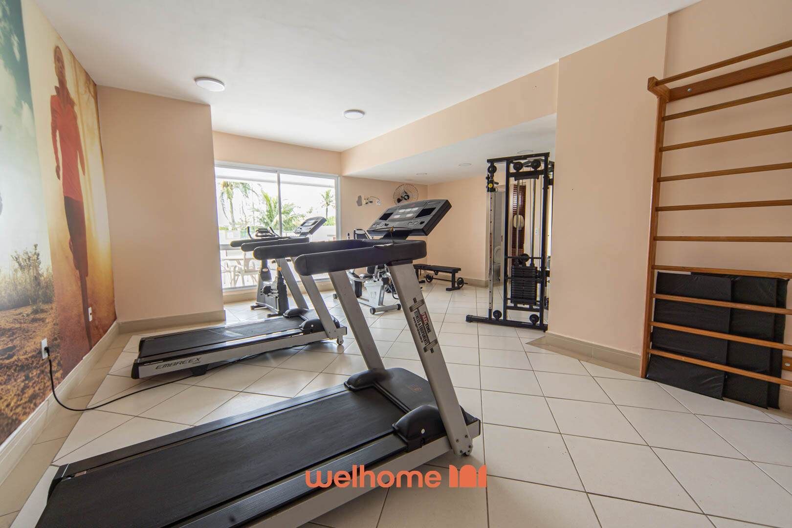 Un gimnasio con cintas de correr, máquinas de pesas y barra para dominadas.