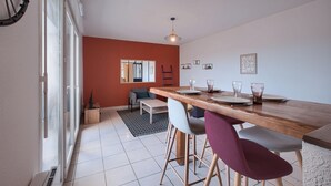 A modern dining area with a wooden table, bar stools, and a black and white patterned rug. - La Grange - Proche Centre & Parking (Laval)