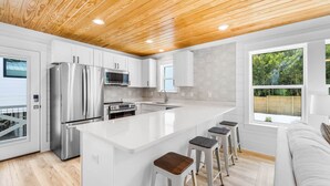 Een moderne keuken met witte kasten, roestvrijstalen apparatuur en een houten plafond.