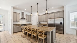 A modern kitchen with a central island, stainless steel appliances, and pendant lighting. - Pelican Perch (Seagrove Beach)