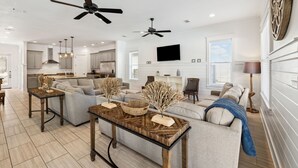 A spacious living room with a large sofa, a coffee table, and two ceiling fans. - Pelican Perch (Seagrove Beach)