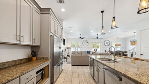 A spacious kitchen with granite countertops, stainless steel appliances, and a central island. - Pelican Perch (Seagrove Beach)