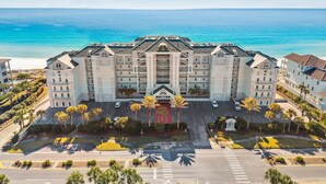 A multi-story hotel with a central courtyard, parking area, and a view of the ocean. - Seabreeze (101B) (Destin)