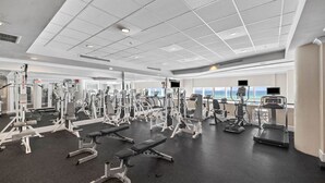 A modern gym with various exercise equipment, large windows, and a view of the ocean. - Seabreeze (101B) (Destin)