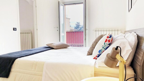 Une chambre à coucher avec un lit, une table de chevet, une lampe et une vue sur l’extérieur.
