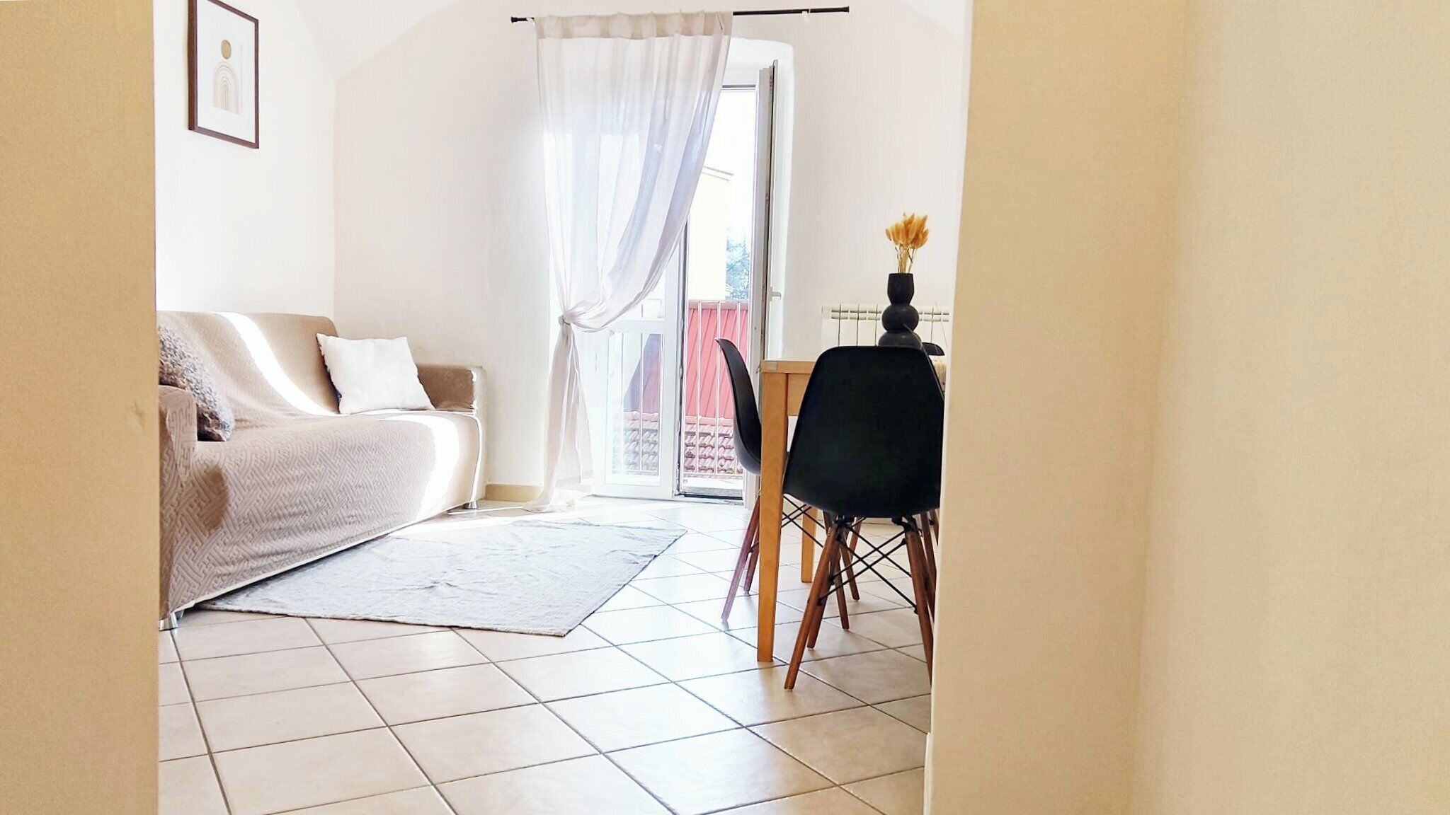 Un salon comprenant un canapé, un fauteuil, une petite table et une vue sur l’extérieur par une porte.