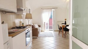 Een kleine keuken met een fornuis, wastafel en een zithoek met een tafel en stoelen.