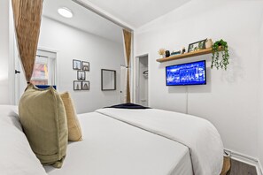 Relax and unwind with the wall-mounted TV right in front of the bed—perfect for movie nights, catching up on your favorite shows, or winding down after a long day. - Sleek 2BR Apt in Times Square (New York)
