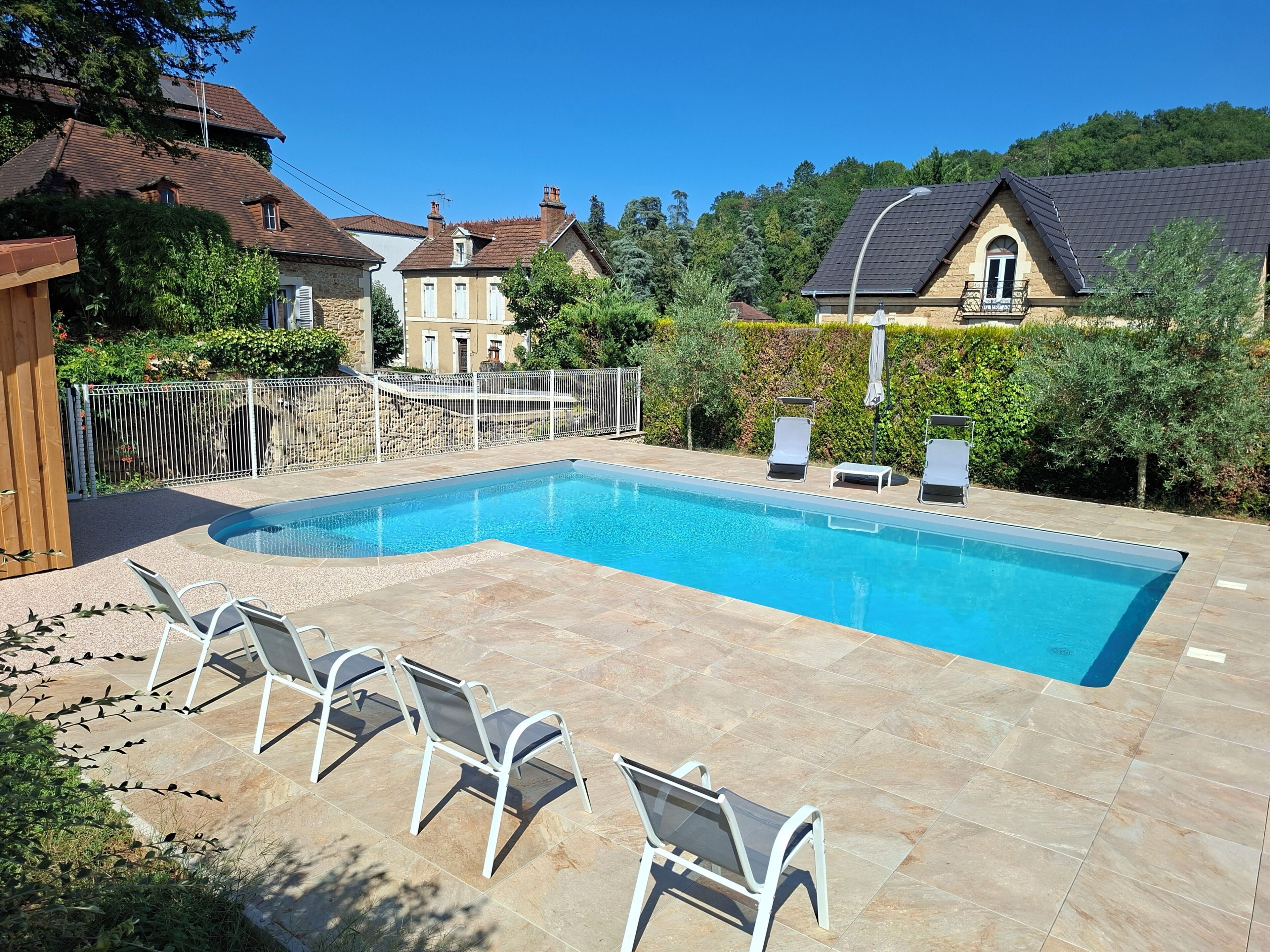 A rectangular swimming pool with a tiled deck, surrounded by lounge chairs.
