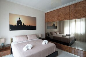 A hotel room with a large bed, a nightstand, a lamp, and a large mirror. - Happio Apartment Appio Latino (Roma)