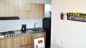 Cocina moderna con armarios de madera, estufa a gas, cafetera y mesa de comedor de vidrio con fruta.