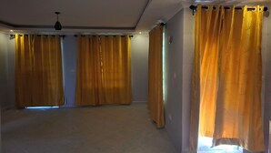 A spacious room with large windows covered by yellow curtains, a tiled floor, and a ceiling with recessed lighting. - Mishen Azure (Naivasha)