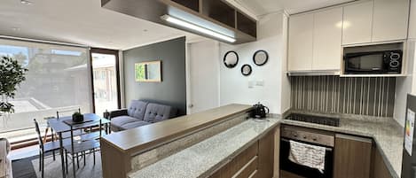 A modern kitchen with a central island, built-in microwave, and a dining area with a sofa and table.