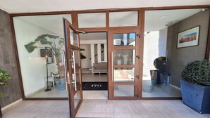 Una entrada moderna con puerta de cristal, felpudo y vista al interior.