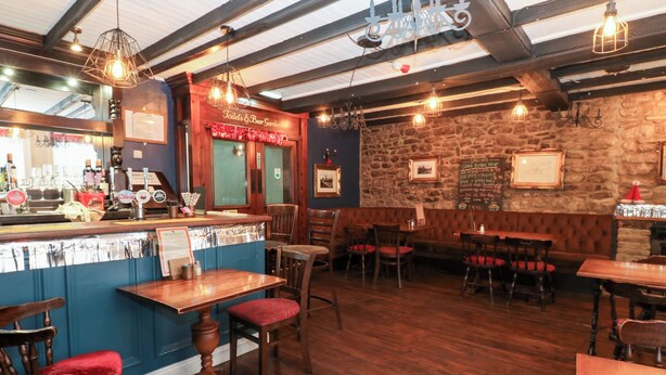 Ein Restaurantinnenraum mit Holztischen und -stühlen, einer Bar und einer Steinwand.