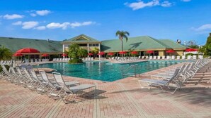 Ein Pool mit Liegestühlen und Sonnenschirmen, umgeben von einem Gebäude mit Gründach.