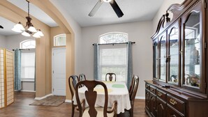 Comedor con una mesa de madera, sillas y un aparador con puertas de vidrio.