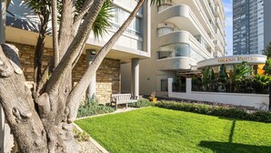 Un hôtel moderne à la façade en pierre, doté d’une pelouse bien entretenue et d’une enseigne bien visible indiquant « Grand Pavillon ».